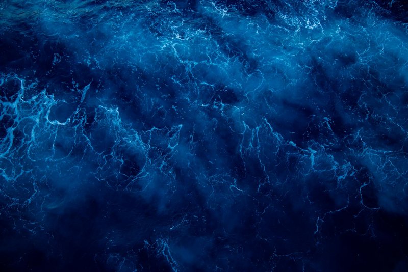 A mesmerizing top view of dark blue ocean waves with a wavy surface and intricate texture.