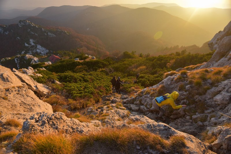 Adventurous hikers ascend rocky terrain in stunning Malo Selo during a beautiful sunset.