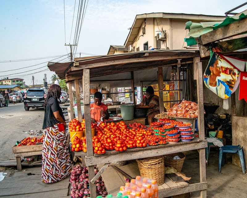 A bustling street market scene showcasing fresh tomatoes and local vendors in a vibrant urban setting.
