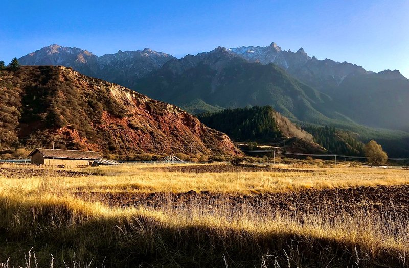 A breathtaking view of mountains and grassy fields under a clear blue sky.