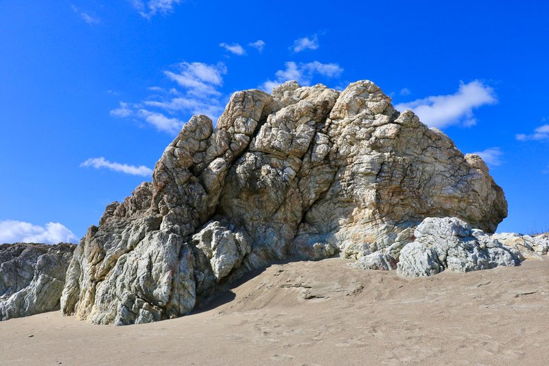 Majestic rock formation under a bright blue sky, showcasing natural beauty and geological wonder.