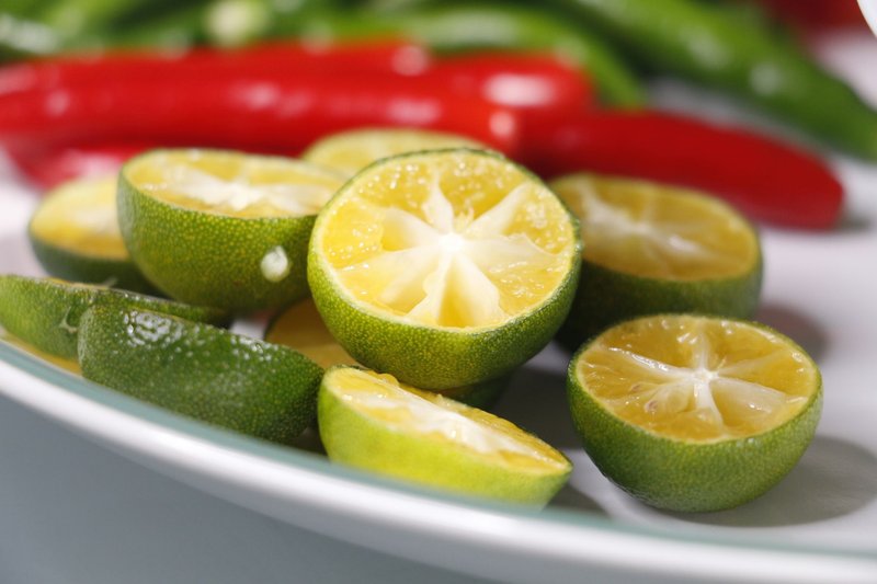 Close-up of freshly sliced calamansi with colorful peppers, showcasing a vibrant culinary contrast.