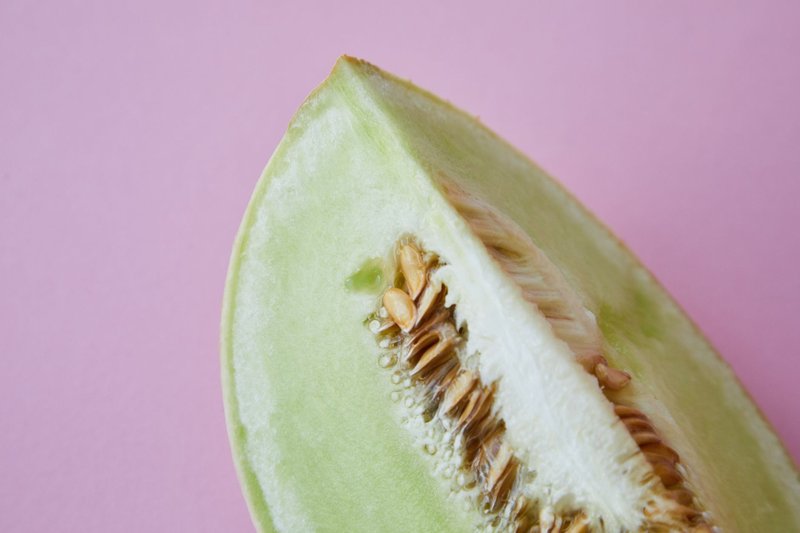 Piece of ripe juicy melon prepared for breakfast on pink background of studio