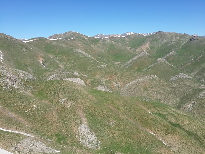 Scenic view of Kurdistan Bozorg's rolling mountains under clear blue skies, perfect for nature exploration.