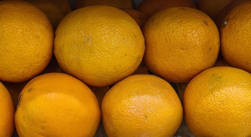 Close-up of ripe oranges stacked together, showcasing vibrant color and texture.